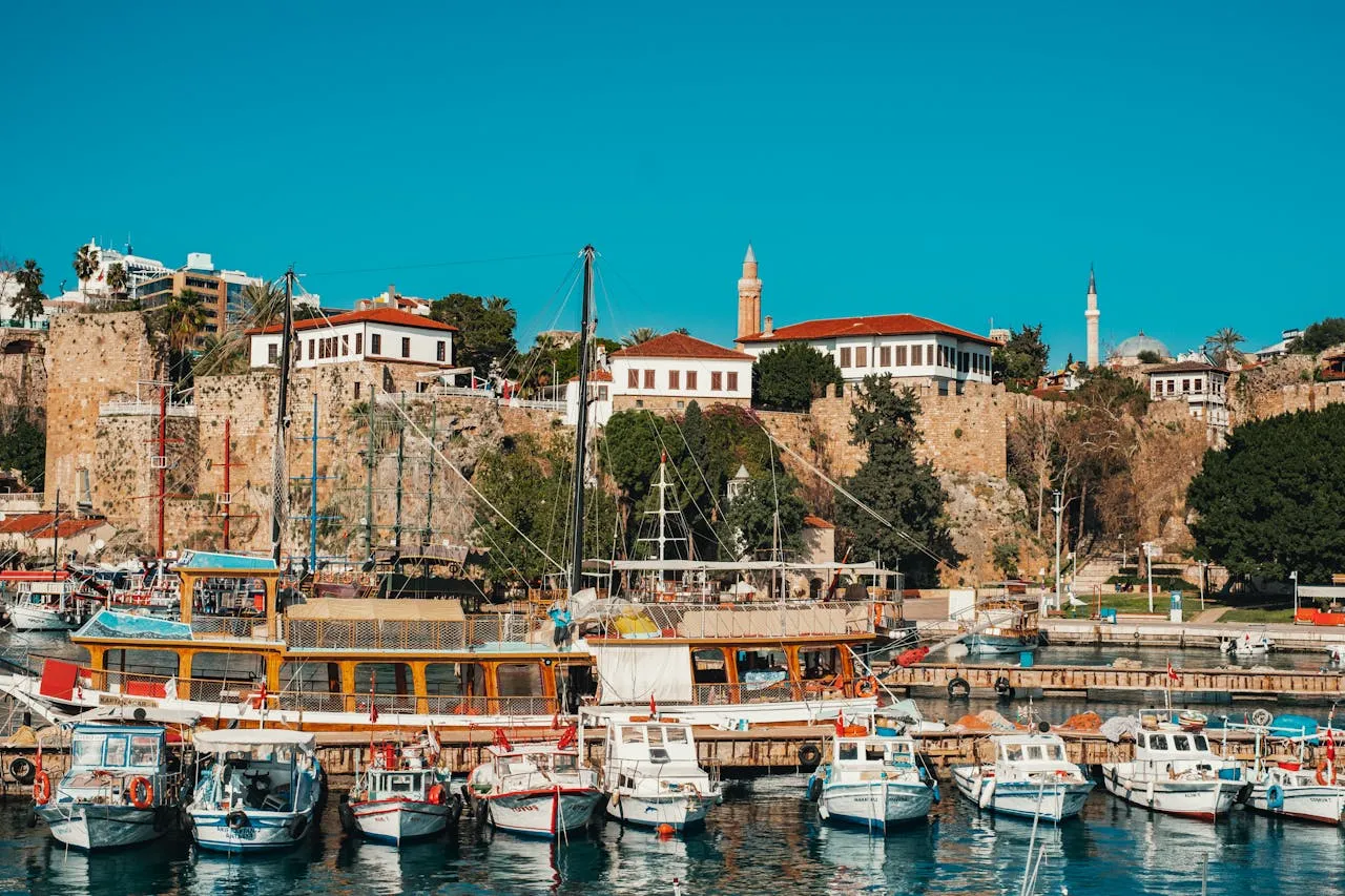 Antalya's historic harbour with traditional boats moored against ancient stone walls — the beautiful coastal setting for dental tourism in Turkey