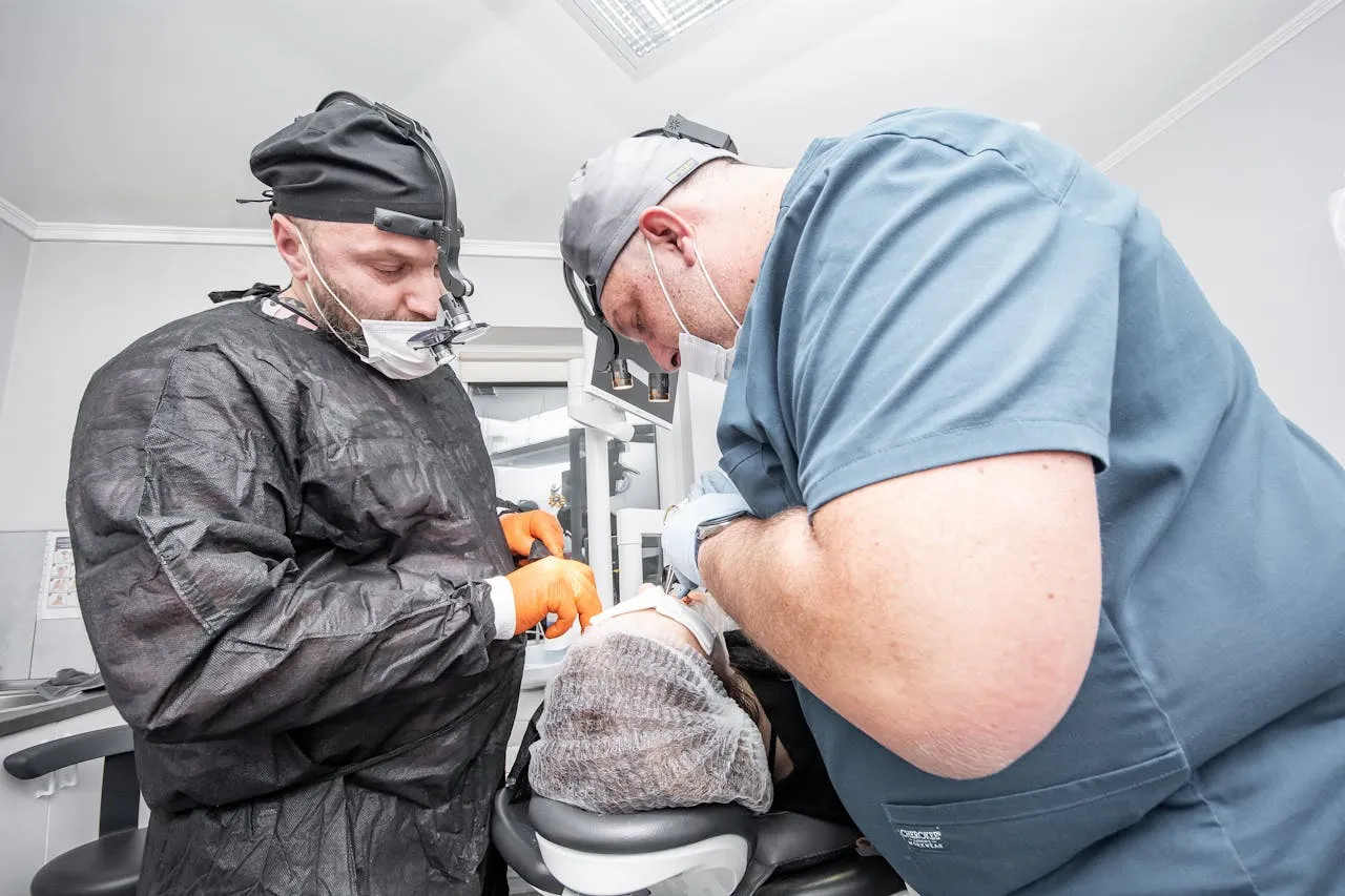 Two dental professionals in surgical scrubs performing a dental implant procedure at an accredited Turkish dental clinic — the specialist team approach at top clinics in Antalya