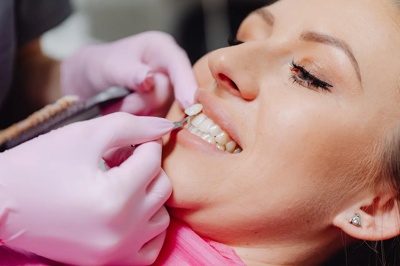 Dentist applying a porcelain veneer to a patient's tooth during a smile makeover procedure — the precise bonding stage at a Turkish cosmetic dental clinic